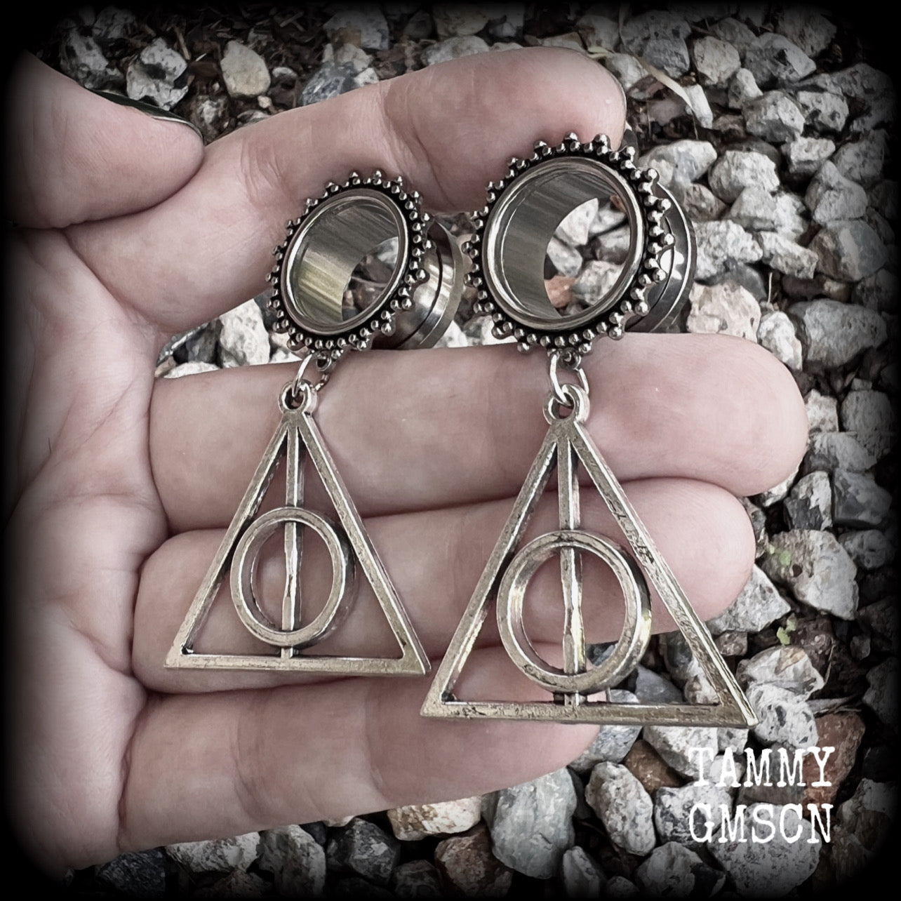 Measuring just on 6 cms from tip to tip, and weighing approx 10 grams a piece, this pair of adorable Harry Potter tunnel dangles features a classic antique silver Deathly Hallows charm.

 This pair has been made with gorgeous boho 5/8" gauge (16mm) ornate surgical steel screw fit tunnels, suitable for stretched lobes. 