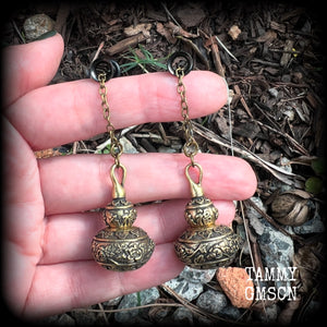 These brass stash pot tunnel dangles are gorgous! 
Featuring tibetan sanscrit and beautiful rose details, these earrings weigh in at approx 17 grams each, and nice and dangly, measuring in at just over 7cm from tip to tip.

These open up (as shown) so you can stash spell affirmations, drugs, precious pet ashes, anything you like really...

💥This listing includes one pair of surgical steel single flared O-ring earlets