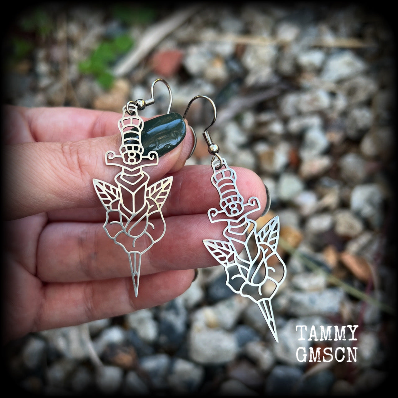 This pair of stainless steel earrings feature a classic punk rose and dagger tattoo design, measuring just on 6.5cms from tip to tip, and weighing only a grams or two each.

This pair has been made on stainless steel french hooks, suitable for pierced ears.