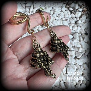 🔥 The three-legged golden toad is a mythological animal in China known to bring prosperity, treasure and wealth. To attract wealth, always have the money toads’ head facing you, and never away from you 🔥

These awesome brass ear hangers feature unique three legged brass money toads, measuring just on 7.5cms from tip to tip, and weighing approx 19 grams each.

This pair has been made on 2 gauge (6mm) titanium coated surgical steel full curls, suitable for stretched lobes.

