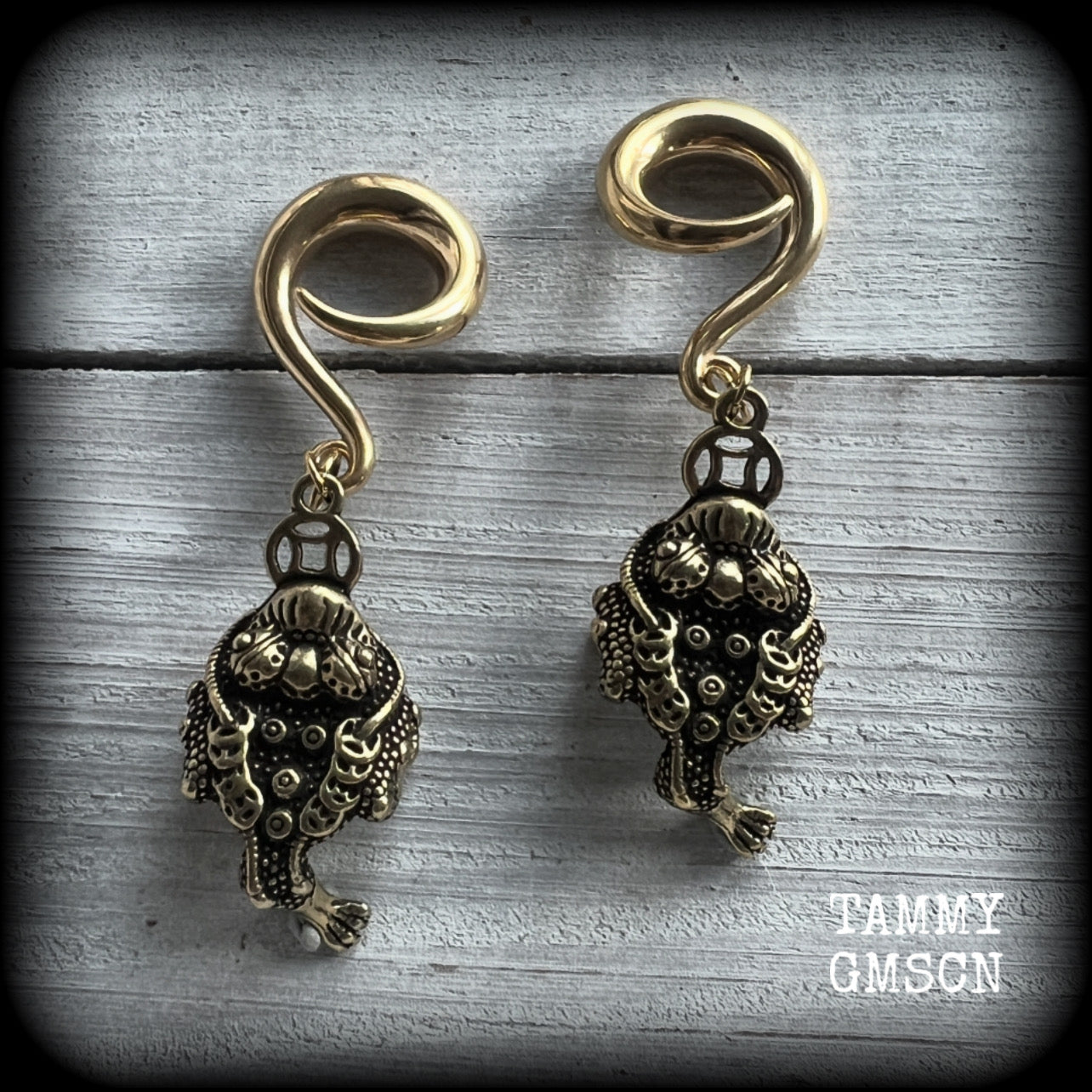 🔥 The three-legged golden toad is a mythological animal in China known to bring prosperity, treasure and wealth. To attract wealth, always have the money toads’ head facing you, and never away from you 🔥

These awesome brass ear hangers feature unique three legged brass money toads, measuring just on 7.5cms from tip to tip, and weighing approx 19 grams each.

This pair has been made on 2 gauge (6mm) titanium coated surgical steel full curls, suitable for stretched lobes.

