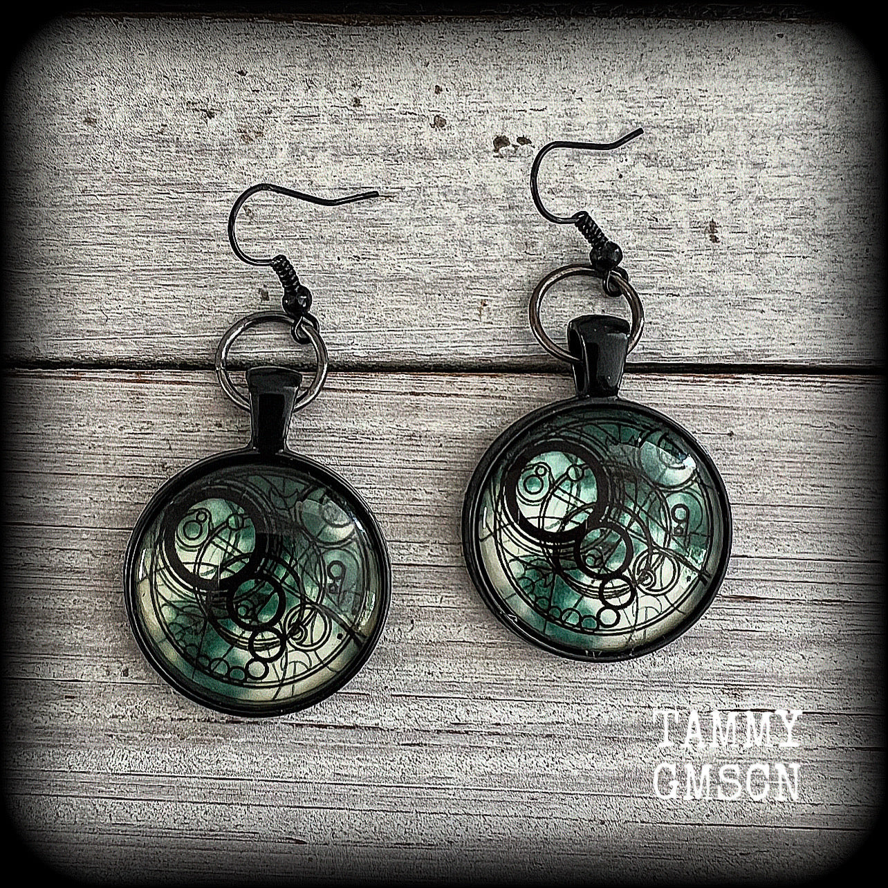 These awesome earrings feature a Dr Who inspired Gallifreyan steampunk sigil enclosed in a shiny resin dome, nice and dangly at just over 6cms from tip to tip, and weighing approx 8 grams a piece.
This pair has been made on french hooks, suitable for pierced ears.