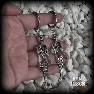 These gorgeous dangly earrings feature antique silver mermaid skeletons, measuring approx 10.5 cms from tip to tip, and weighing approx 14 grams a piece .

These earrings have been made on strong silver alloy snap hoop rings, to be worn in stretched lobes with silicone earlets from 2 gauge (6mm).