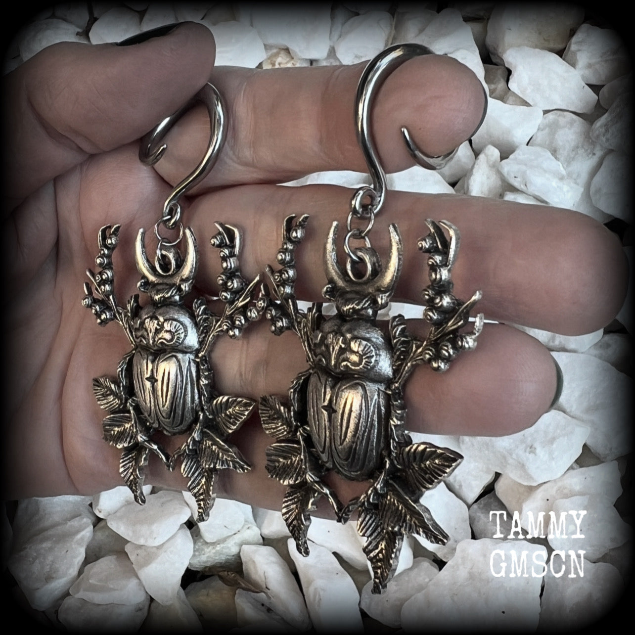 These gorgeous earrings feature large antique silver scarab beetles surrounded by berries and leaves with a crescent moon, measuring approx 7.5cms from tip to tip, and weigh 15 grams a piece.

This pair has been made on 6 gauge (4mm) gauge surgical steel full curls, to be worn in stretched lobes.
