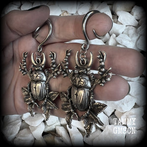 These gorgeous earrings feature large antique silver scarab beetles surrounded by berries and leaves with a crescent moon, measuring approx 7.5cms from tip to tip, and weigh 15 grams a piece.

This pair has been made on 6 gauge (4mm) gauge surgical steel full curls, to be worn in stretched lobes.