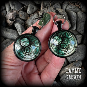 These awesome earrings feature a Dr Who inspired Gallifreyan steampunk sigil enclosed in a shiny resin dome, nice and dangly at just over 6cms from tip to tip, and weighing approx 8 grams a piece.
This pair has been made on french hooks, suitable for pierced ears.