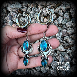 These earrings feature gorgeous facet blue topaz gemstones in a beautiful boho antique silver setting, lovely and dangly at just on 8cms from tip to tip, and not too heavy at 12 grams each.

These earrings have been made on 3/4” gauge (19mm) surgical steel cradles, to be worn in stretched lobes.