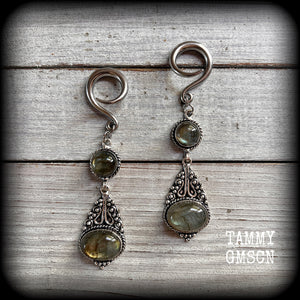 Made with shimmering polished labradorite gemstones, measuring 8.5cms from tip to tip, and weighing approx 10 grams each, not too heavy...
These earrings have been made on 6 gauge (4mm) surgical steel full curl hooks, to be worn in stretched lobes.