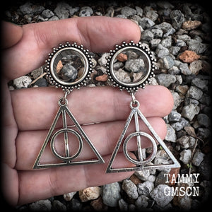 Measuring just on 6 cms from tip to tip, and weighing approx 10 grams a piece, this pair of adorable Harry Potter tunnel dangles features a classic antique silver Deathly Hallows charm.

 This pair has been made with gorgeous boho 5/8" gauge (16mm) ornate surgical steel screw fit tunnels, suitable for stretched lobes. 