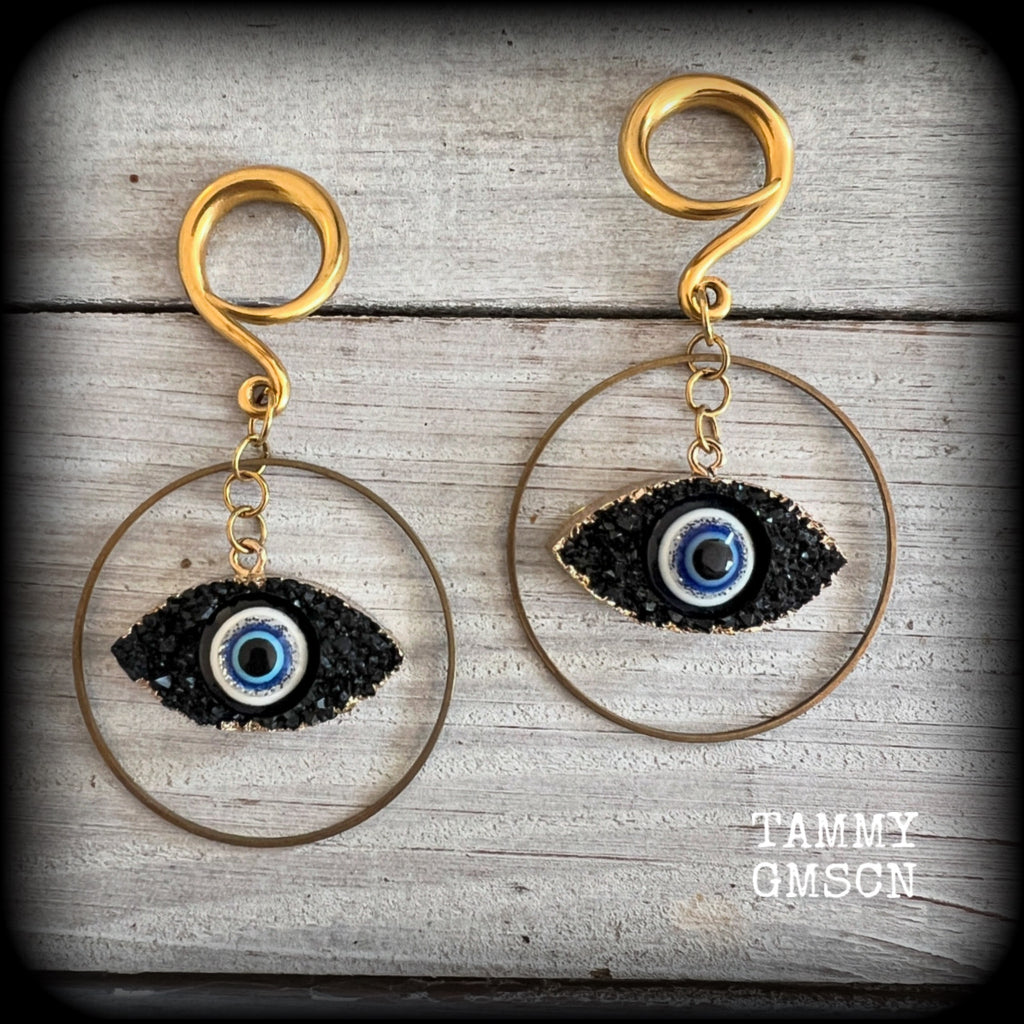 These unique evil eye gauged earrings feature a faux druzy greek evil eye, weighing approx 6 grams each, and are nice and dangly, hanging just on 7cms from tip to tip.

This pair have been made on 6 gauge (4mm) surgical steel full curl hooks, suitable for stretched lobes.