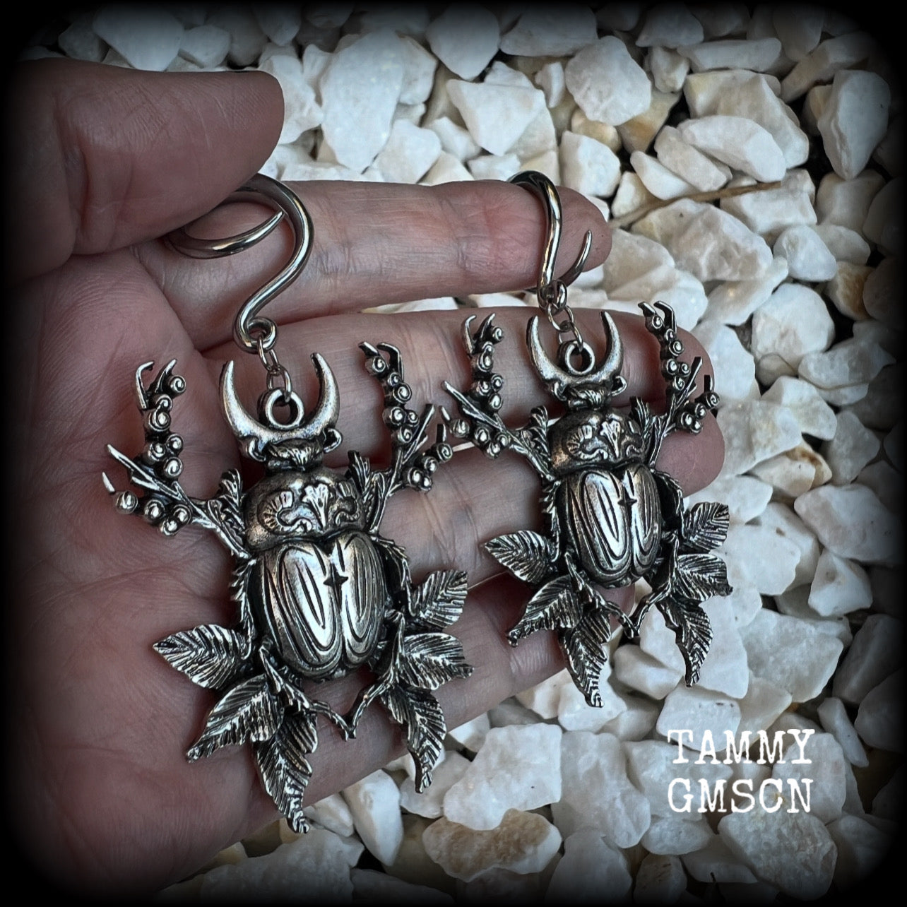 These gorgeous earrings feature large antique silver scarab beetles surrounded by berries and leaves with a crescent moon, measuring approx 7.5cms from tip to tip, and weigh 15 grams a piece.

This pair has been made on 6 gauge (4mm) gauge surgical steel full curls, to be worn in stretched lobes.
