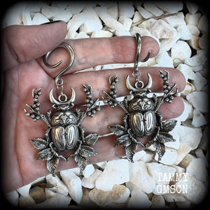 These gorgeous earrings feature large antique silver scarab beetles surrounded by berries and leaves with a crescent moon, measuring approx 7.5cms from tip to tip, and weigh 15 grams a piece.

This pair has been made on 6 gauge (4mm) gauge surgical steel full curls, to be worn in stretched lobes.