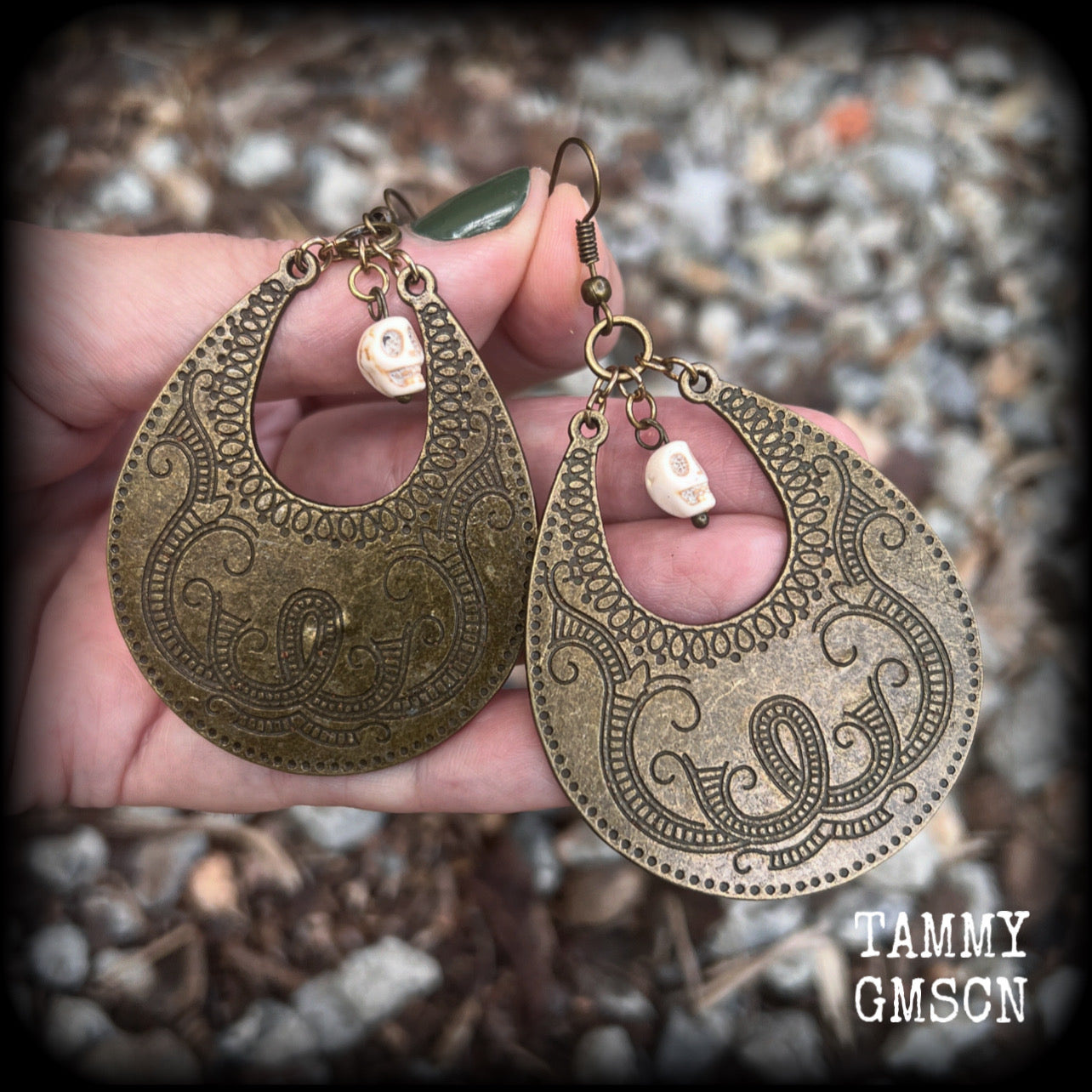 Inspired by Voodoo Sky-father Damballah, these earrings feature bone white skulls hanging from gorgeous antique bronze tear drop discs etched with a beautiful abstract serpent pattern.
Measuring 8cms from tip to tip, these unique earrings weigh 12 grams each, and have been made on antique bronze french hooks, suitable for pierced ears.