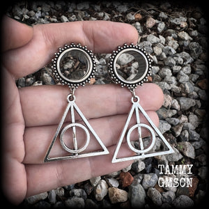 Measuring just on 6 cms from tip to tip, and weighing approx 10 grams a piece, this pair of adorable Harry Potter tunnel dangles features a classic antique silver Deathly Hallows charm.

 This pair has been made with gorgeous boho 5/8" gauge (16mm) ornate surgical steel screw fit tunnels, suitable for stretched lobes. 