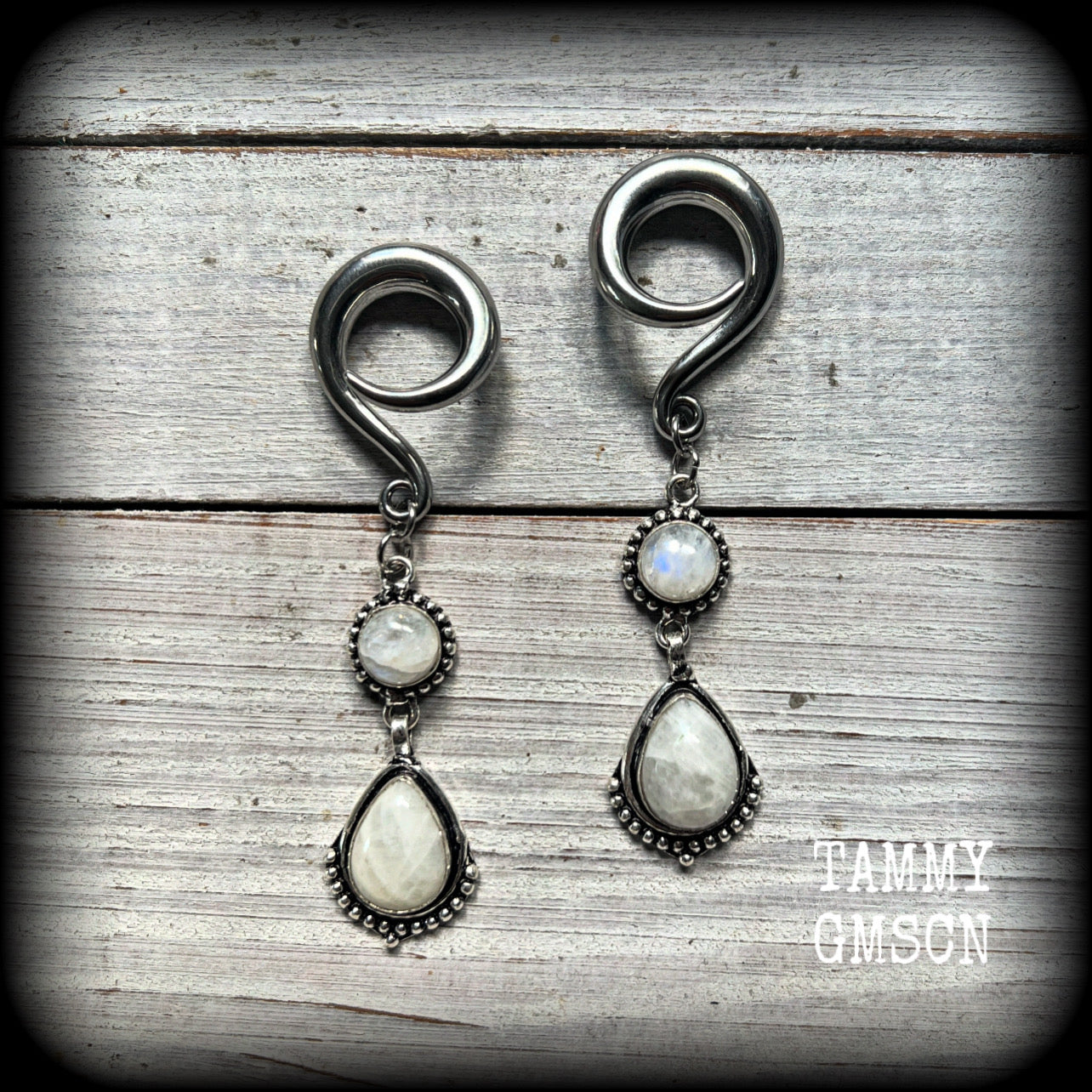 These gorgeous earrings feature polished Rainbow Moonstone gemstones in a beautiful boho antique silver setting, lovely and dangly at approx 7.5cms from tip to tip, and not too heavy at 13 grams each.
This pair had been made on 2 gauge (6mm) surgical steel full curls, to be worn in stretched lobes.