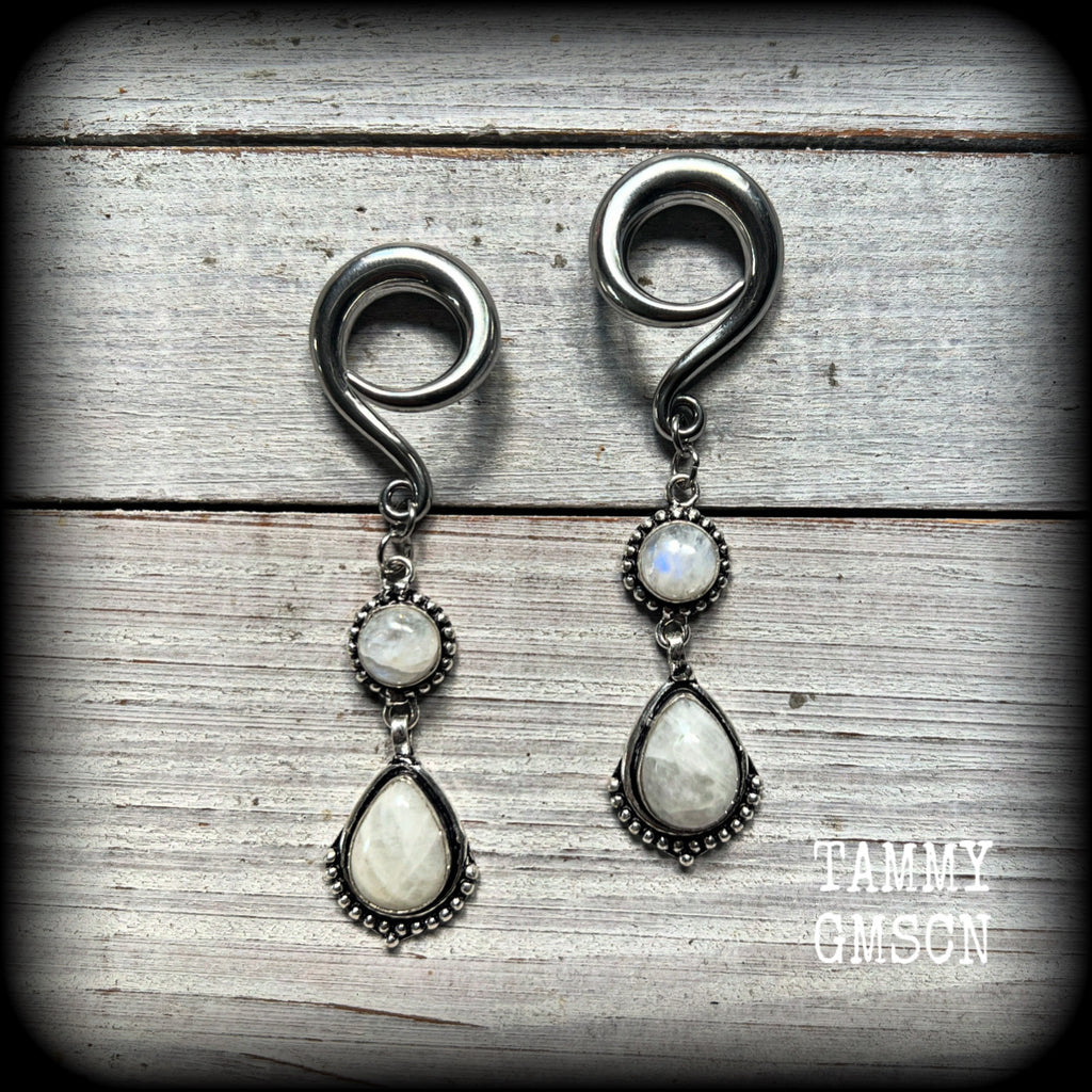 These gorgeous earrings feature polished Rainbow Moonstone gemstones in a beautiful boho antique silver setting, lovely and dangly at approx 7.5cms from tip to tip, and not too heavy at 13 grams each.
This pair had been made on 2 gauge (6mm) surgical steel full curls, to be worn in stretched lobes.