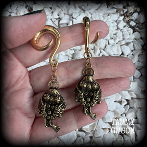 🔥 The three-legged golden toad is a mythological animal in China known to bring prosperity, treasure and wealth. To attract wealth, always have the money toads’ head facing you, and never away from you 🔥

These awesome brass ear hangers feature unique three legged brass money toads, measuring just on 7.5cms from tip to tip, and weighing approx 19 grams each.

This pair has been made on 2 gauge (6mm) titanium coated surgical steel full curls, suitable for stretched lobes.

