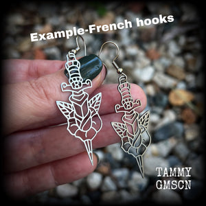 This pair of stainless steel earrings feature a classic punk rose and dagger tattoo design, measuring just on 6.5cms from tip to tip, and weighing only a grams or two each.

This pair has been made on stainless steel french hooks, suitable for pierced ears.