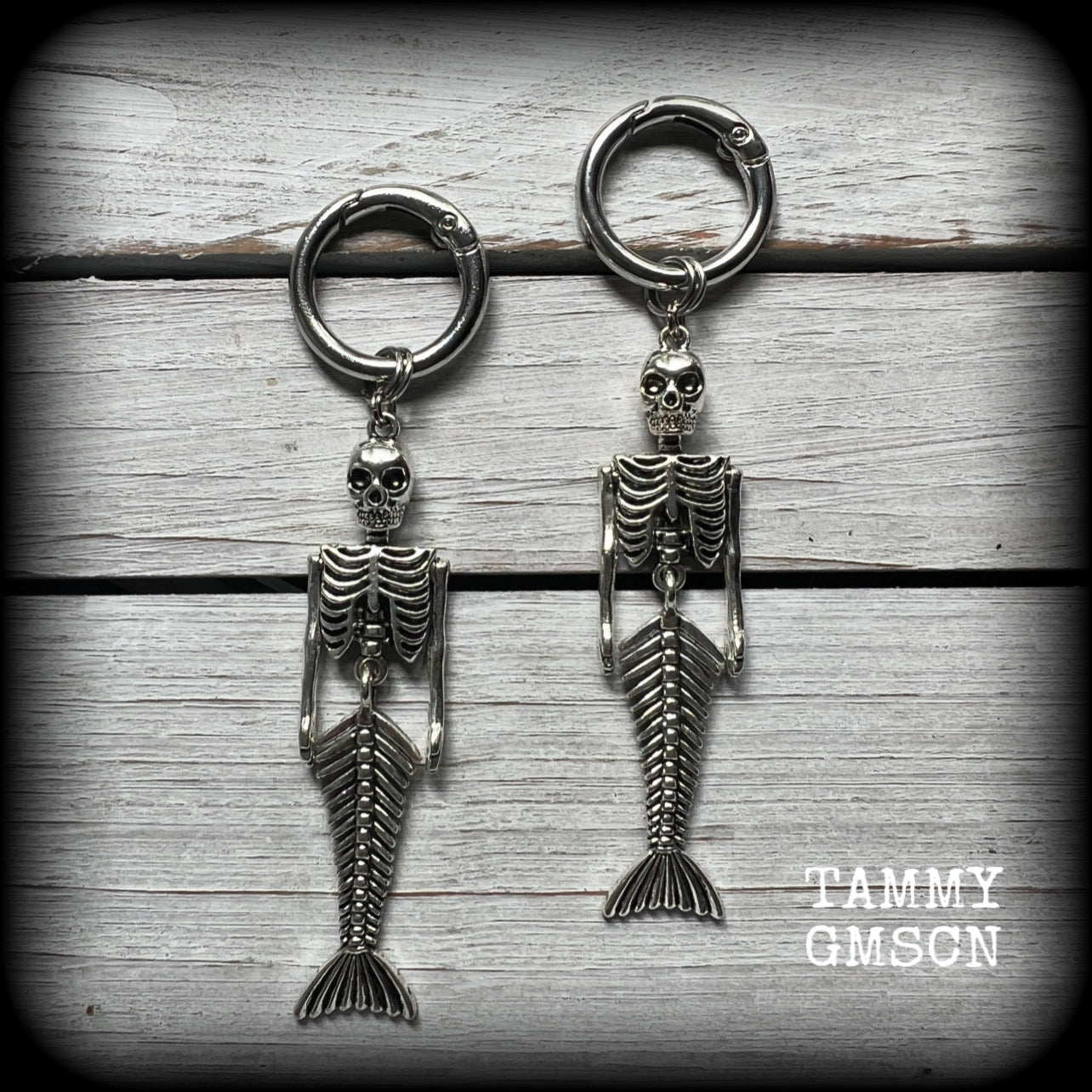 These gorgeous dangly earrings feature antique silver mermaid skeletons, measuring approx 10.5 cms from tip to tip, and weighing approx 14 grams a piece .

These earrings have been made on strong silver alloy snap hoop rings, to be worn in stretched lobes with silicone earlets from 2 gauge (6mm).