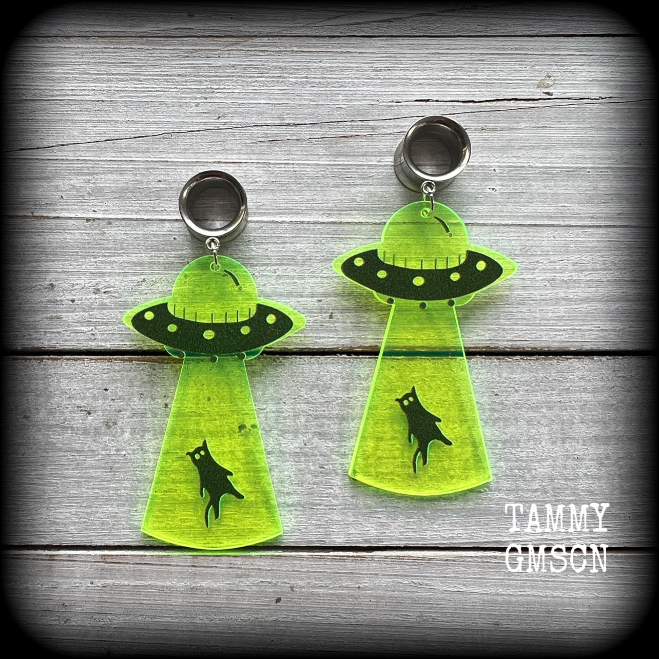 These awesome tunnel earrings feature gorgeous green and black acrylic UFO charms beaming up a poor unsuspecting cat, classic!
These tunnel dangles are nice and light weight, weighing only 6 grams each, and measuring just on 8cms from tip to tip.

This pair have been made with 1/2" gauge (12mm) surgical steel screw fit earlets.