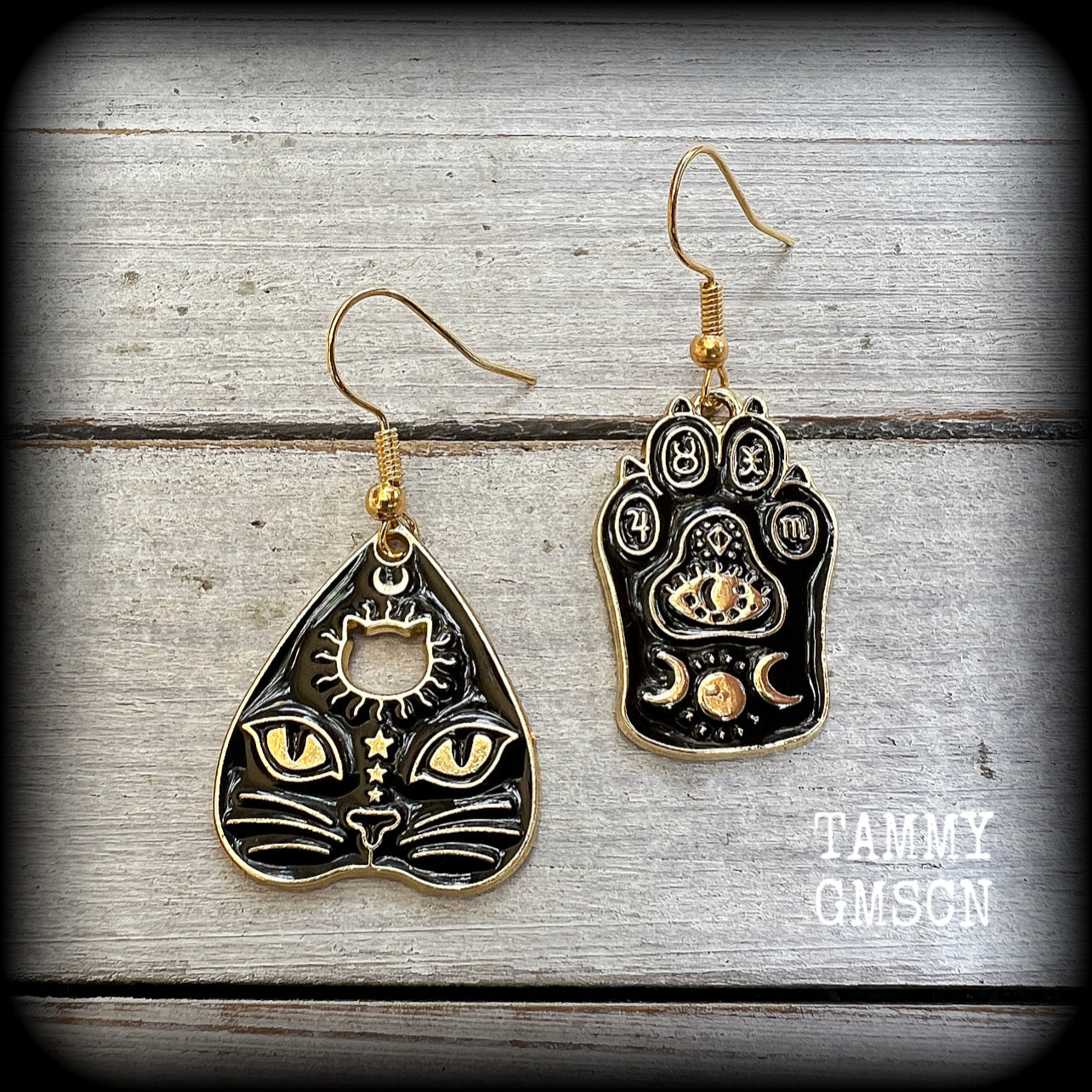 These adorable occult cat planchette and paw earrings feature classic antique gold and enamel ouija board planchette and paw charms adorned with crescent moons and planetary sigils.

These earrings are lovely and light weight at only a few grams a piece, and measure just under 5cms from tip to tip.