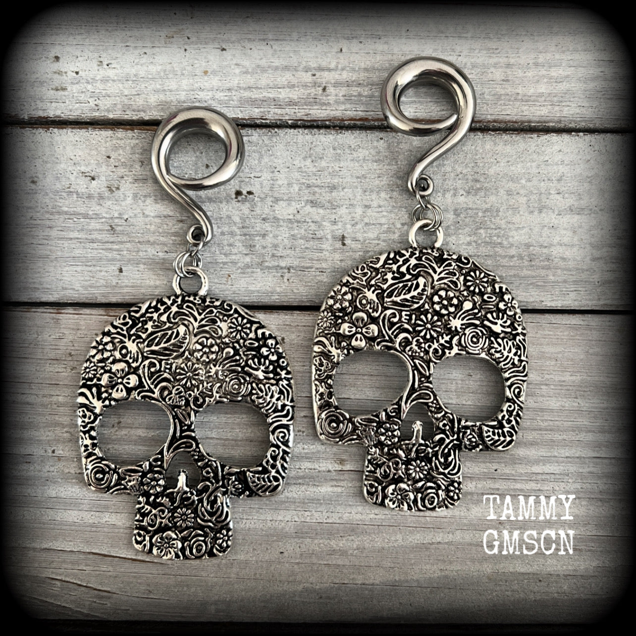 Featuring large antique silver skulls with floral detail, these earrings are perfect for Day of the Dead celebrations!

These gorgeous earrings weigh in at approx. 20 grams a piece, and nice and dangly at just under 10cms from tip to tip.

This pair of beautiful gauged earrings has been made with 2 gauge (6mm) surgical steel full curl hooks, suitable for stretched lobes.