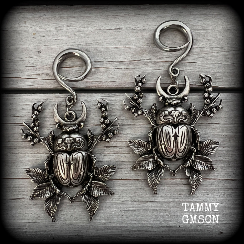 These gorgeous earrings feature large antique silver scarab beetles surrounded by berries and leaves with a crescent moon, measuring approx 7.5cms from tip to tip, and weigh 15 grams a piece.

This pair has been made on 6 gauge (4mm) gauge surgical steel full curls, to be worn in stretched lobes.
