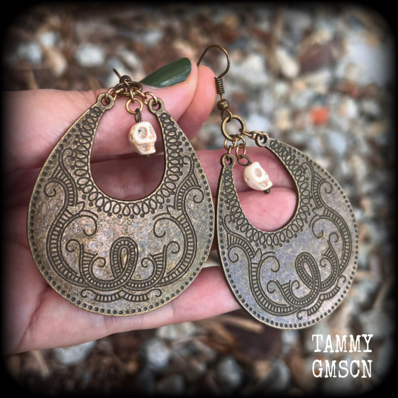 Inspired by Voodoo Sky-father Damballah, these earrings feature bone white skulls hanging from gorgeous antique bronze tear drop discs etched with a beautiful abstract serpent pattern.
Measuring 8cms from tip to tip, these unique earrings weigh 12 grams each, and have been made on antique bronze french hooks, suitable for pierced ears.