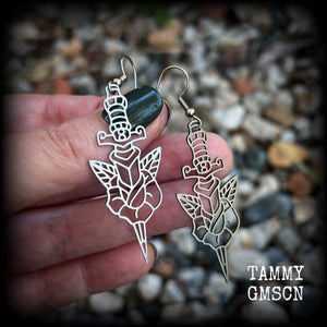 This pair of stainless steel earrings feature a classic punk rose and dagger tattoo design, measuring just on 6.5cms from tip to tip, and weighing only a grams or two each.

This pair has been made on stainless steel french hooks, suitable for pierced ears.