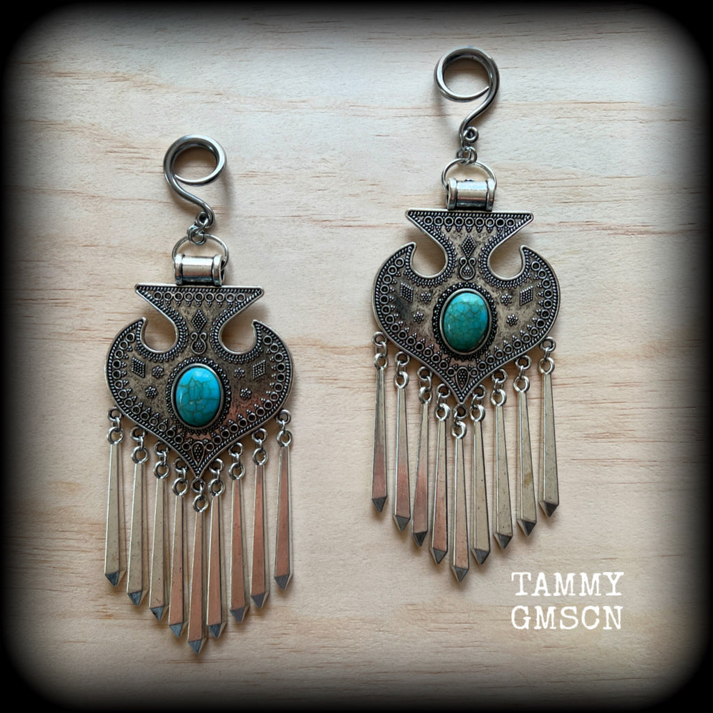 Inspired by Hathor, these unique ethnic inspired gauged earrings feature gorgeous antique silver pendants with beautiful turquoise stones.
These are gorgeous statement ear hangers, measuring just under 15cms from tip to tip and weighing in at 45 grams each they do have a nice bit of weight to them.

This pair has been made on 6 gauge (4mm) surgical steel full curl hooks, to be worn in stretched lobes.