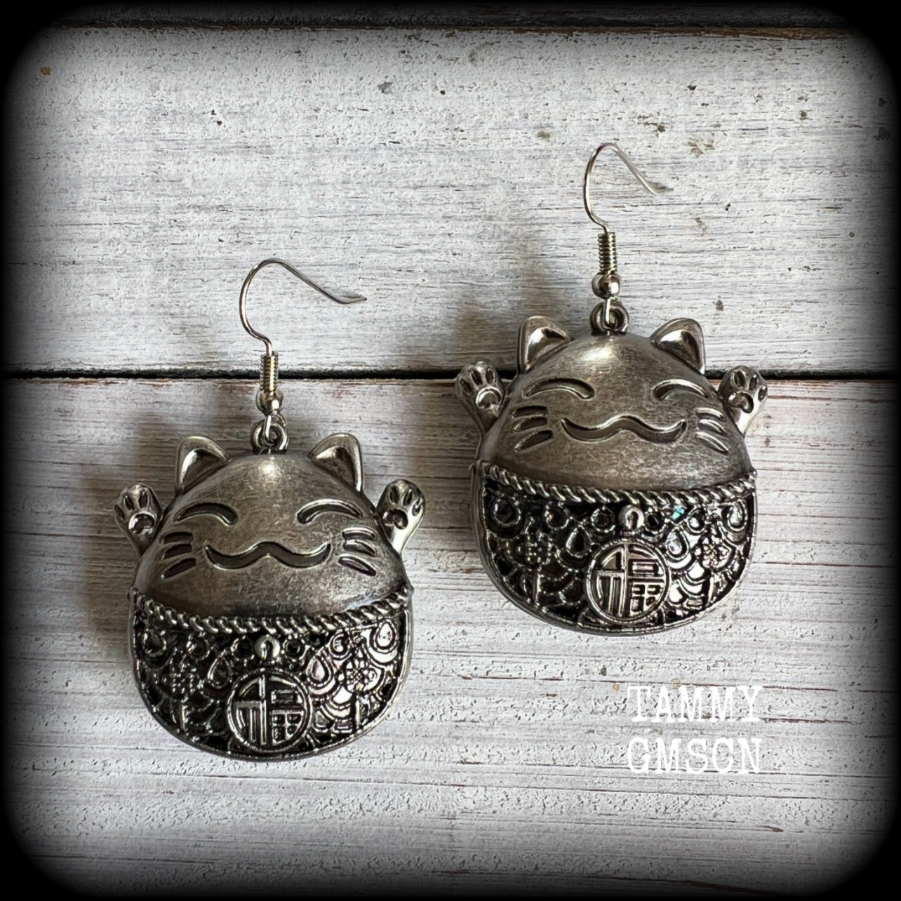These gorgeous earrings features antique silver happy cat charms with the symbol for ‘good fortune’ on its tummy, measuring just on 5cms from tip to tip, and weighing approx 8 grams each.

This pair have been made on stainless steel french hooks, for pierced ears.