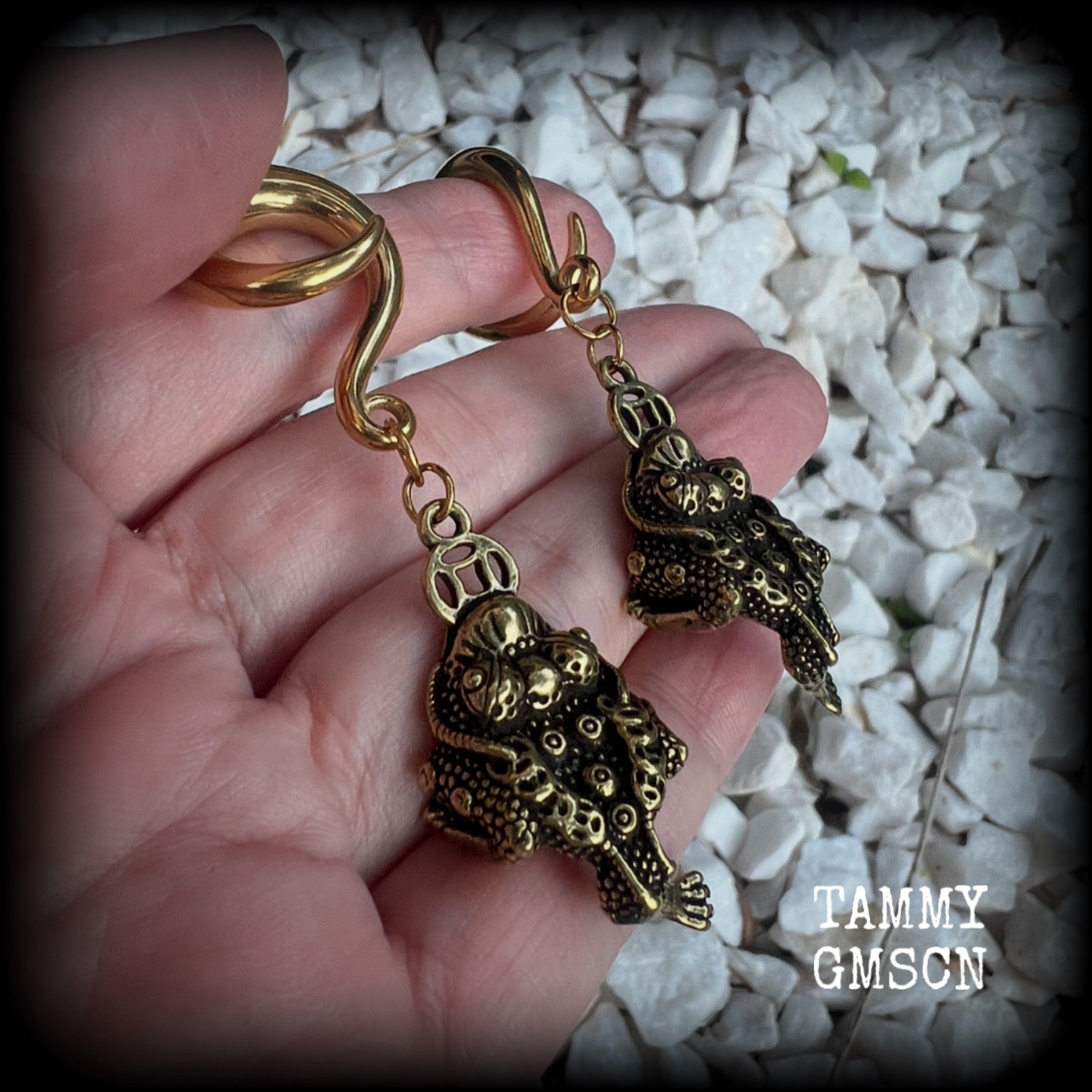 🔥 The three-legged golden toad is a mythological animal in China known to bring prosperity, treasure and wealth. To attract wealth, always have the money toads’ head facing you, and never away from you 🔥

These awesome brass ear hangers feature unique three legged brass money toads, measuring just on 7.5cms from tip to tip, and weighing approx 19 grams each.

This pair has been made on 2 gauge (6mm) titanium coated surgical steel full curls, suitable for stretched lobes.

