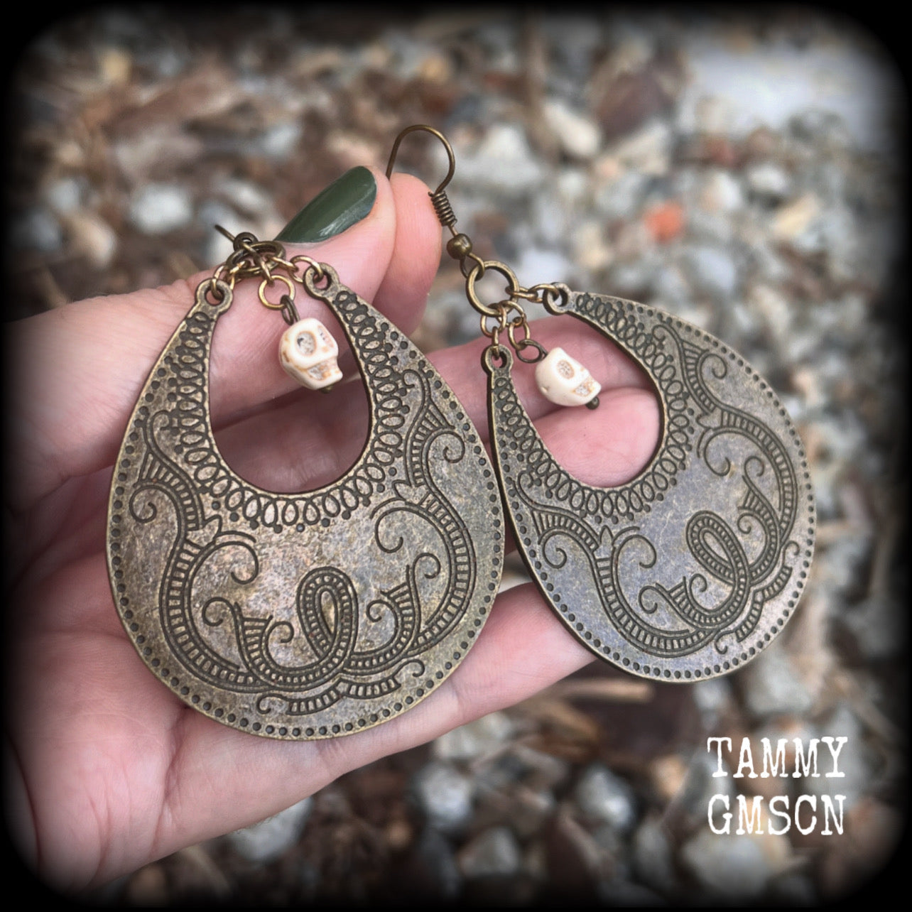 Inspired by Voodoo Sky-father Damballah, these earrings feature bone white skulls hanging from gorgeous antique bronze tear drop discs etched with a beautiful abstract serpent pattern.
Measuring 8cms from tip to tip, these unique earrings weigh 12 grams each, and have been made on antique bronze french hooks, suitable for pierced ears.