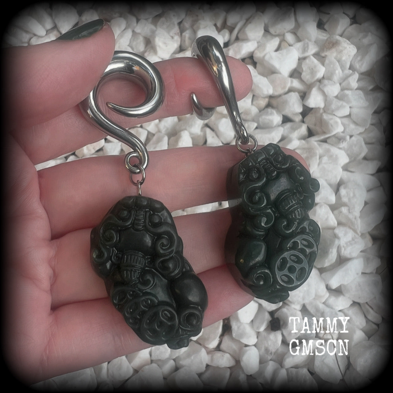 These gorgeous earrings are made from carved Lantian jade featuring the beautiful mythological lion dog, the Pi Xiu, weighing approx 34 grams a piece and measure just over 7cms from tip to tip.

This pair have been made with 0 gauge (8mm) surgical steel full curl hooks, to be worn in stretched lobes.