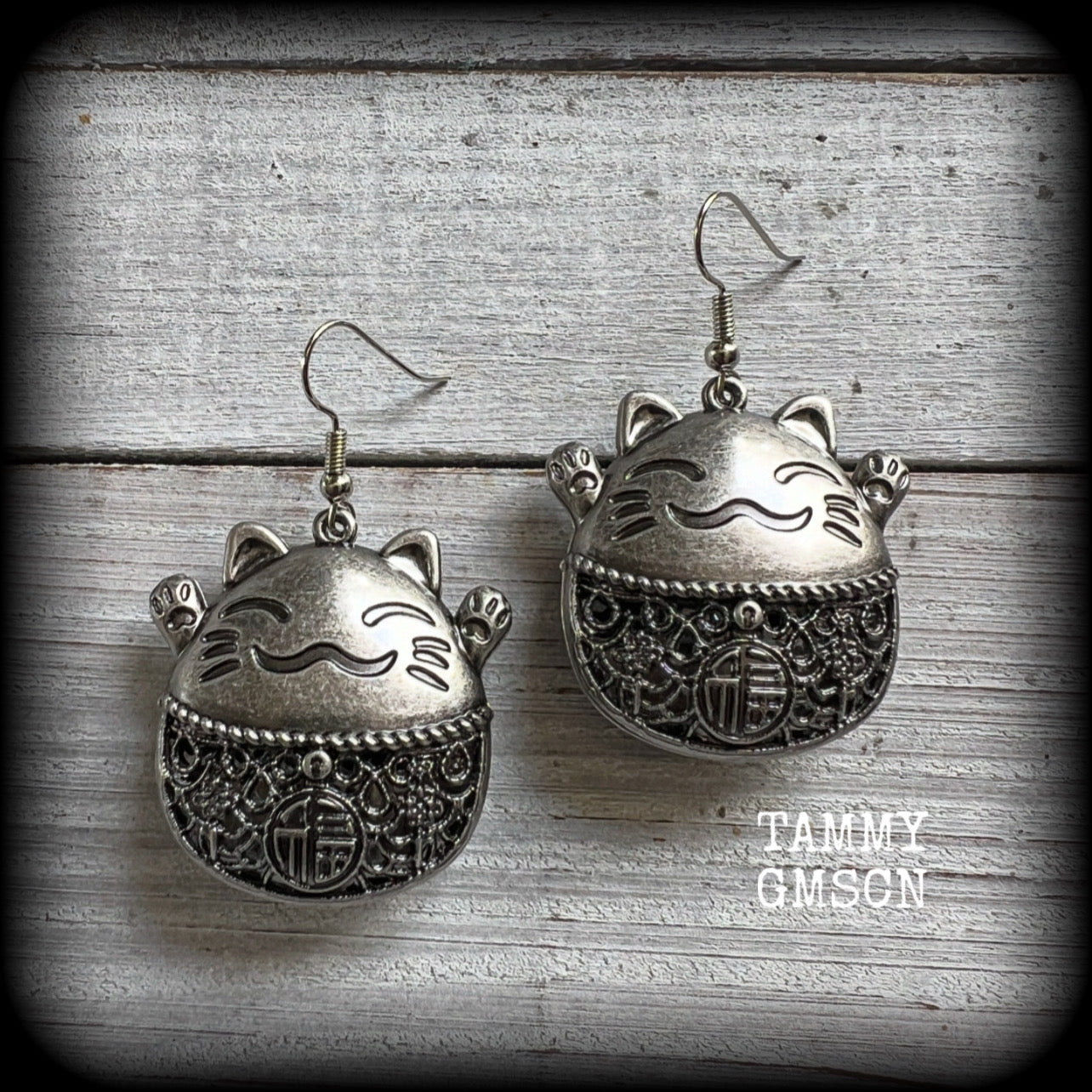 These gorgeous earrings features antique silver happy cat charms with the symbol for ‘good fortune’ on its tummy, measuring just on 5cms from tip to tip, and weighing approx 8 grams each.

This pair have been made on stainless steel french hooks, for pierced ears.