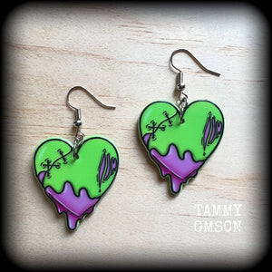 These awesome 'Zombie heart' earrings feature light weight purple and green acrylic rotting zombie hearts, are super lightweight at only 3 grams each, and are nice and dangly, measuring just under 6cms from tip to tip.

This pair has made on stainless steel french hooks, suitable for pierced ears or stretched lobes.