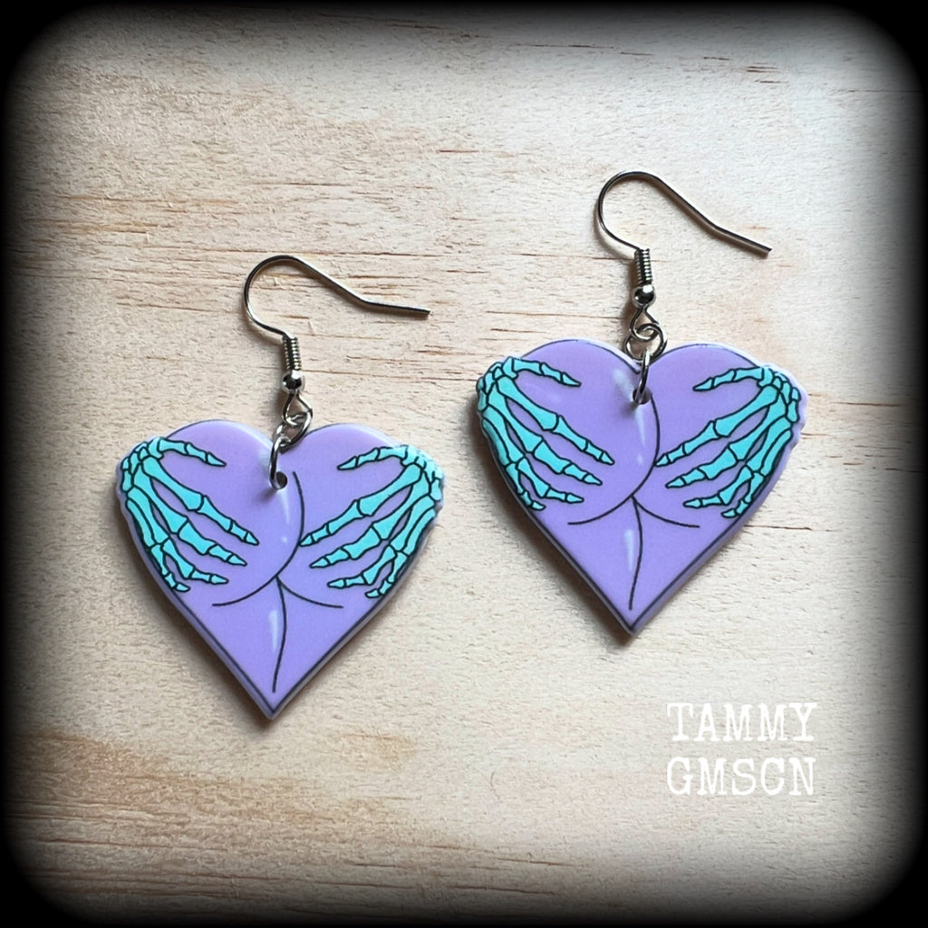 These cheeky pastel goth halloween earrings feature light weight skeleton hands grabbing a pair of purple butt cheeks, super lightweight at only a few grams each, and nice and dangly at 6cms from tip to tip.

This pair has made on stainless steel french hooks, suitable for pierced ears.