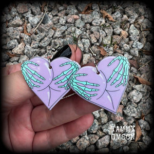 These cheeky pastel goth halloween earrings feature light weight skeleton hands grabbing a pair of purple butt cheeks, super lightweight at only a few grams each, and nice and dangly at 6cms from tip to tip.  This pair has made on stainless steel french hooks, suitable for pierced ears.