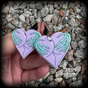 These cheeky pastel goth halloween earrings feature light weight skeleton hands grabbing a pair of purple butt cheeks, super lightweight at only a few grams each, and nice and dangly at 6cms from tip to tip.  This pair has made on stainless steel french hooks, suitable for pierced ears.