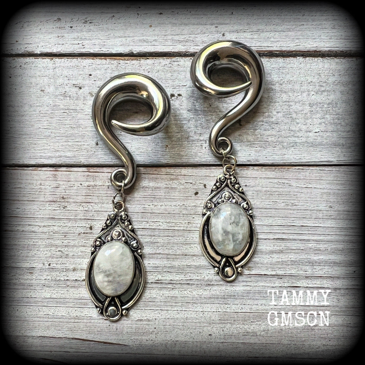 This pair of Rainbow moonstone gauged earrings feature gorgeous polished gemstones in a beautiful boho antique silver setting, lovely and dangly measuring approx 8cms from tip to tip, and weighing approx 27 grams each.

These earrings have been made on 00 gauge (10mm) surgical steel full curls, to be worn in stretched lobes.