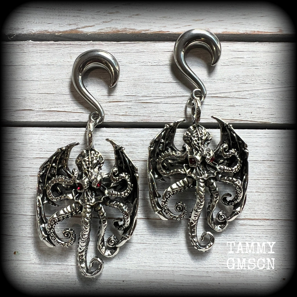These ungodly gauged earrings feature big beautiful antique silver winged Cthulhu charms with glowing red eyes, weighing in at 33 grams a piece, and measure just on 9.5cms from tip to tip.

This pair has been made on 0 gauge (8mm) surgical steel half curl hooks, suitable for stretched lobes.