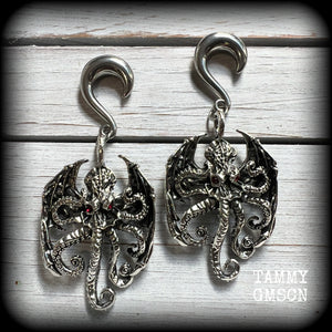 These ungodly gauged earrings feature big beautiful antique silver winged Cthulhu charms with glowing red eyes, weighing in at 33 grams a piece, and measure just on 9.5cms from tip to tip.

This pair has been made on 0 gauge (8mm) surgical steel half curl hooks, suitable for stretched lobes.