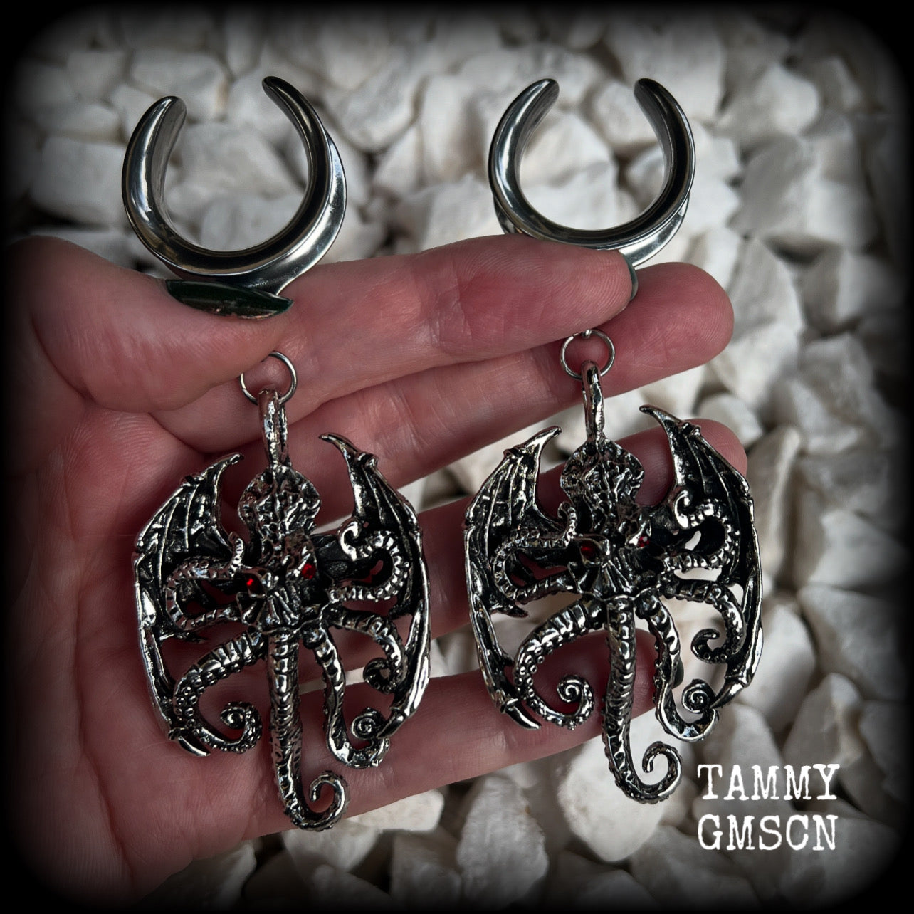 These ungodly gauged earrings feature big beautiful antique silver winged Cthulhu charms with glowing red eyes, weighing in at 33 grams a piece, and measure just over 10cms from tip to tip.  This pair has been made on 1” gauge (25mm) surgical steel full cradles, suitable for stretched lobes.
