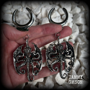 These ungodly gauged earrings feature big beautiful antique silver winged Cthulhu charms with glowing red eyes, weighing in at 33 grams a piece, and measure just over 10cms from tip to tip.  This pair has been made on 1” gauge (25mm) surgical steel full cradles, suitable for stretched lobes.