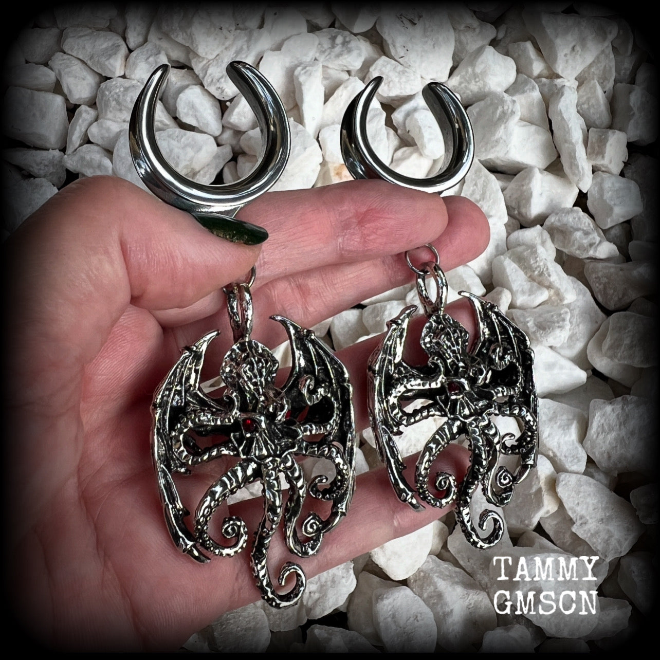 These ungodly gauged earrings feature big beautiful antique silver winged Cthulhu charms with glowing red eyes, weighing in at 33 grams a piece, and measure just over 10cms from tip to tip.  This pair has been made on 1” gauge (25mm) surgical steel full cradles, suitable for stretched lobes.