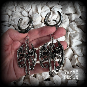 These ungodly gauged earrings feature big beautiful antique silver winged Cthulhu charms with glowing red eyes, weighing in at 33 grams a piece, and measure just over 10cms from tip to tip.  This pair has been made on 1” gauge (25mm) surgical steel full cradles, suitable for stretched lobes.
