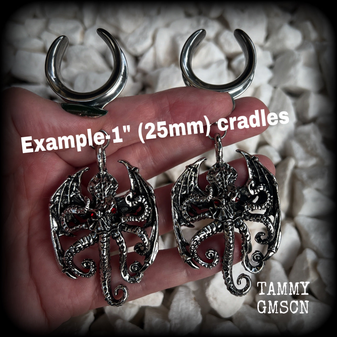These ungodly gauged earrings feature big beautiful antique silver winged Cthulhu charms with glowing red eyes, weighing in at 33 grams a piece, and measure just over 10cms from tip to tip.  This pair has been made on 1” gauge (25mm) surgical steel full cradles, suitable for stretched lobes.