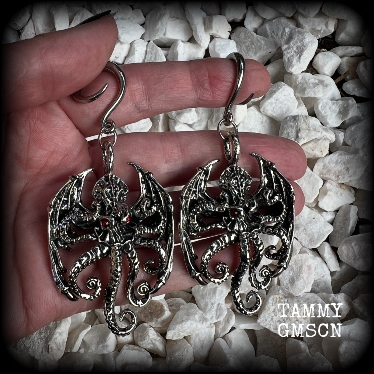 These ungodly gauged earrings feature big beautiful antique silver winged Cthulhu charms with glowing red eyes, weighing in at 27 grams a piece, and measure just over 9cms from tip to tip.  This pair has been made on 6 gauge (4mm) surgical steel full curl hooks, suitable for stretched lobes.