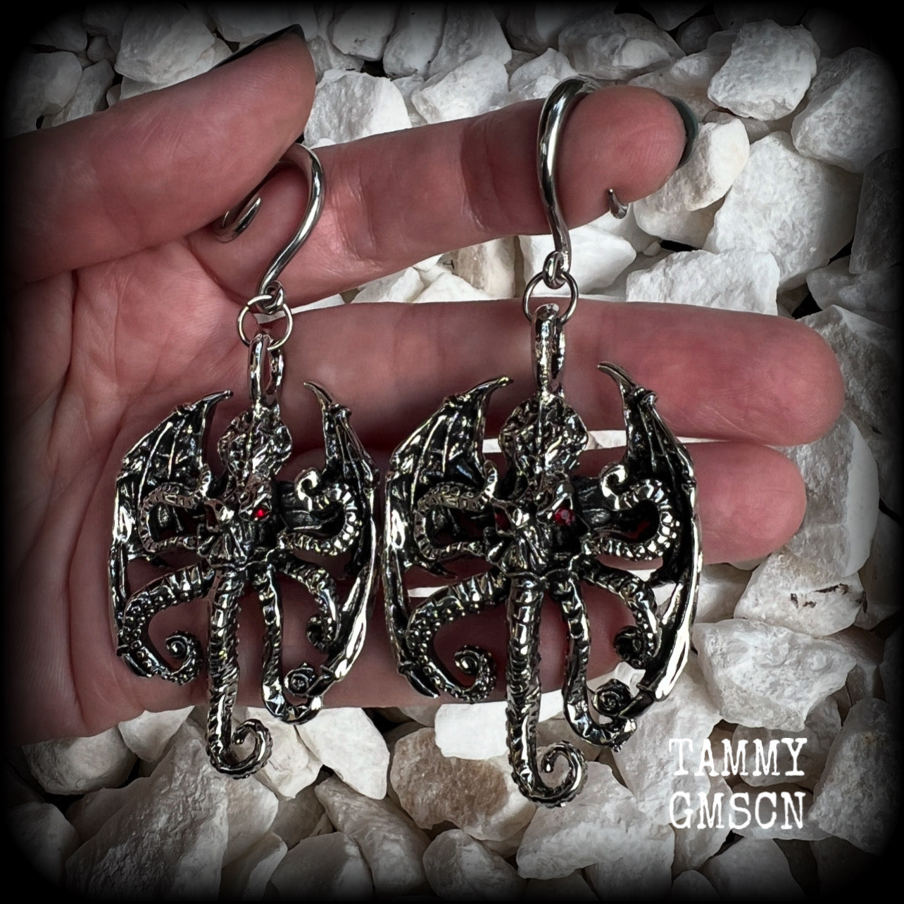 These ungodly gauged earrings feature big beautiful antique silver winged Cthulhu charms with glowing red eyes, weighing in at 27 grams a piece, and measure just over 9cms from tip to tip.  This pair has been made on 6 gauge (4mm) surgical steel full curl hooks, suitable for stretched lobes.