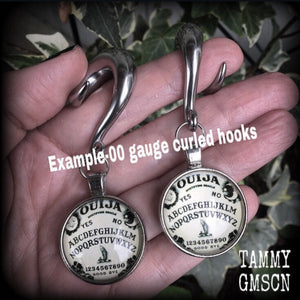 Featuring a double sided Ouija board dome pendant, these awesome earrings weigh approx 32 grams a piece, and measure just on 8cms from tip to tip.

This pair have been made with 00 gauge (10mm) surgical steel full curl hooks, suitable for stretched lobes.

